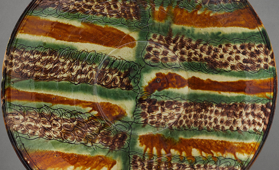 A brown, green, and yellow earthenware dish that originates from 10th-century Iran